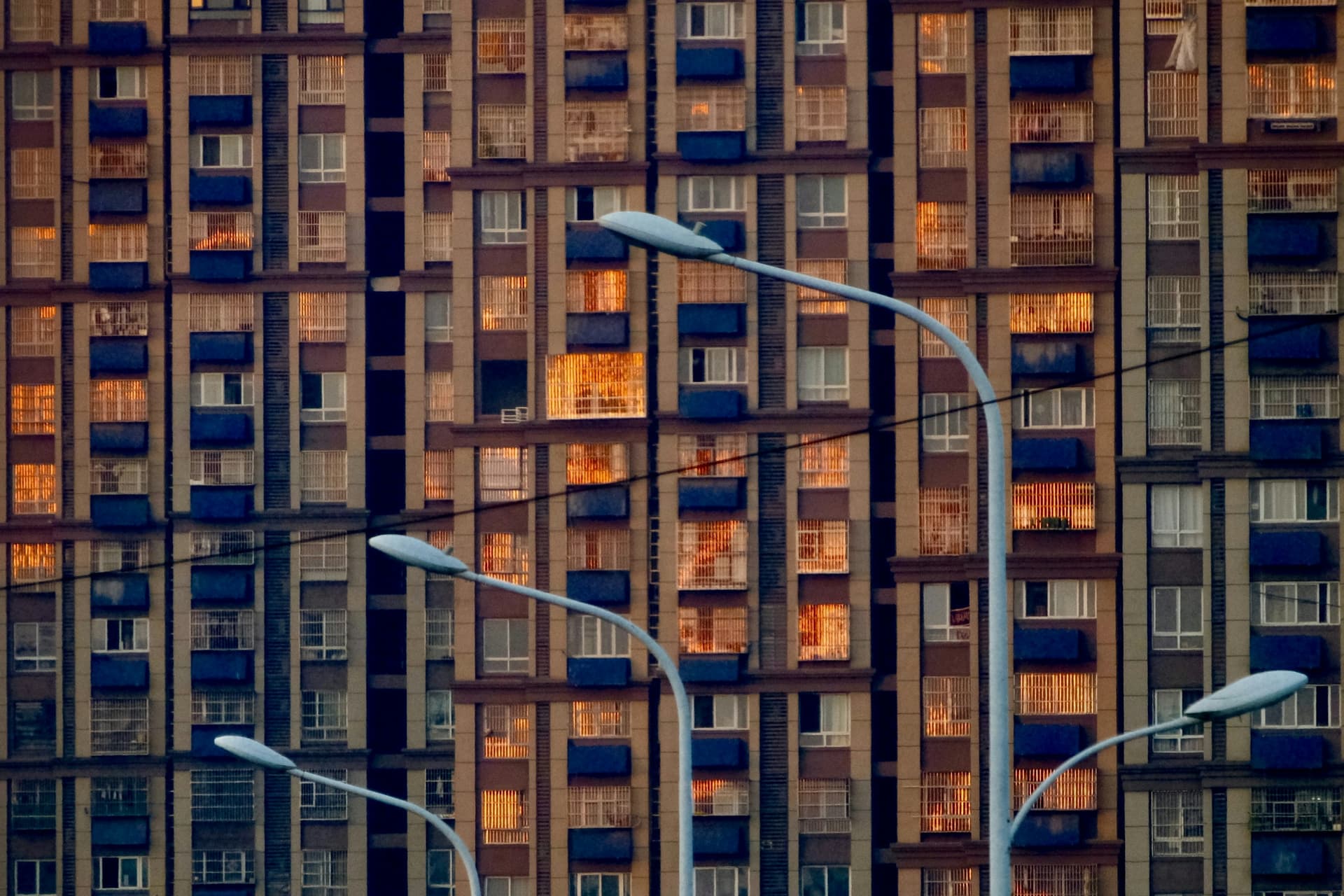 Apartment building facade with glowing windows at sunset