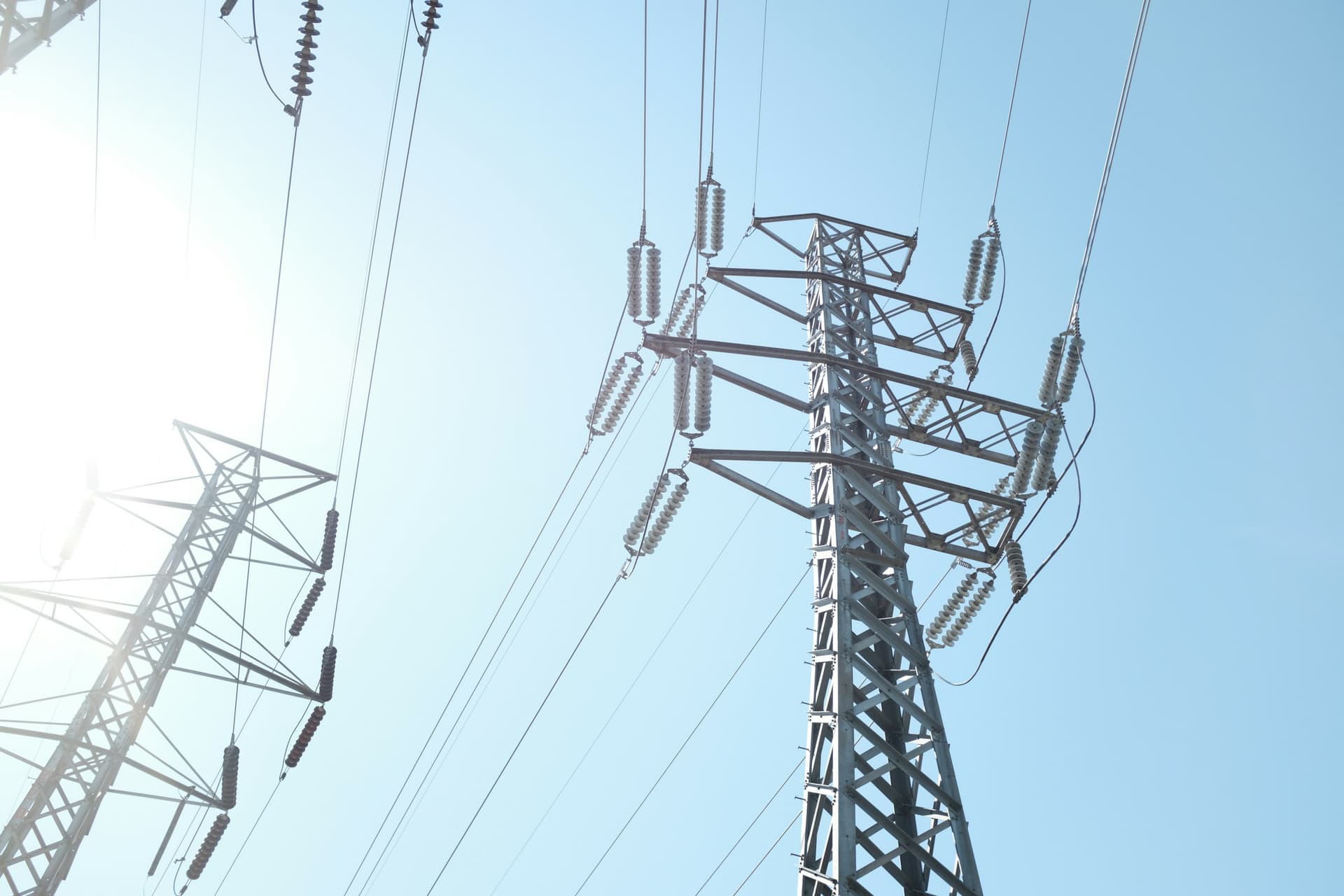 High-voltage transmission towers seen from below against a pale sky