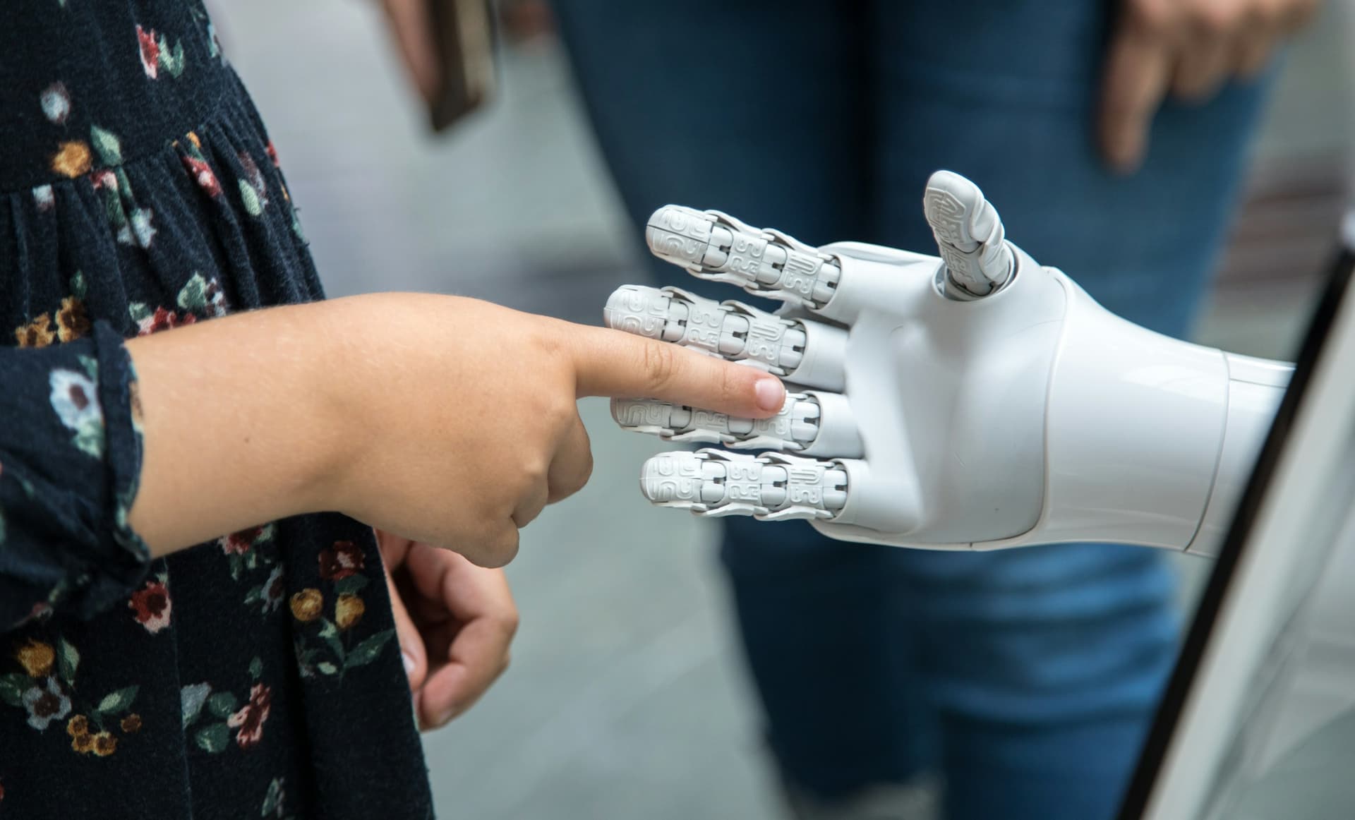 Un bambino che tocca il dito di una mano robotica bianca
